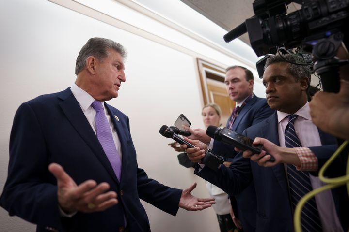 Sen. Joe Manchin (D-W.Va.) is met by reporters outside the hearing room where he chairs the Senate Committee on Energy and Natural Resources on July 21. The legislation he supports on health care and climate change has solid support from voters, a new Democratic survey finds.