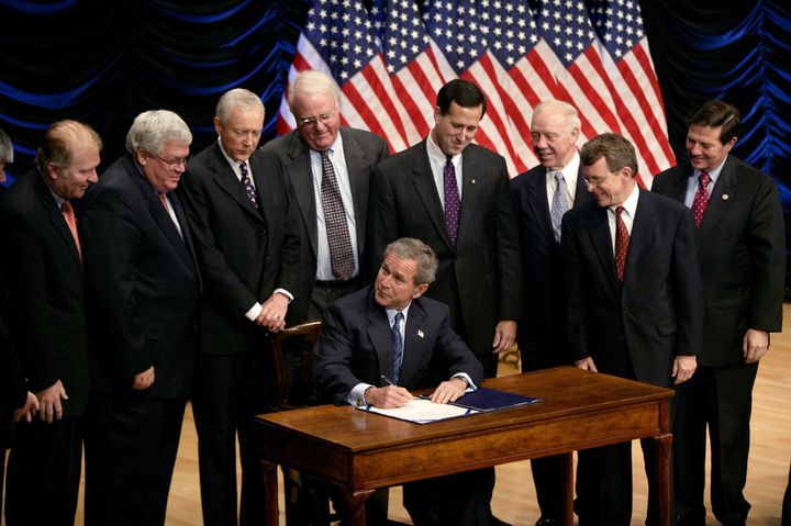 Surrounded by male Republican lawmakers, President George W. Bush signs legislation banning so-called "partial-birth" abortions.
