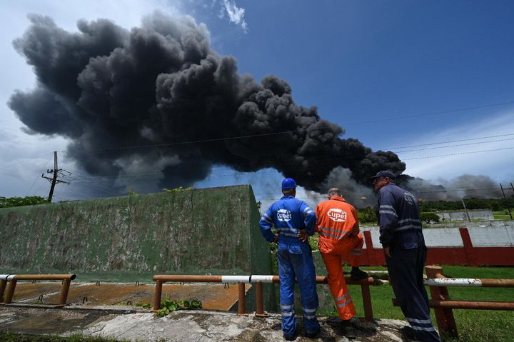 Cuban Petroleum (CUPET) workers look at black smoke near an oil tank fire in Matanzas, Cuba.