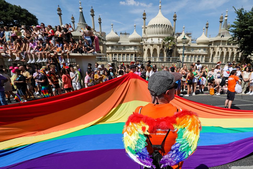 BRIGHTON, ENGLAND - AUGUST 06: Festival goers watch a rainbow flag being carried at the Pride LGBTQ+ Community Parade – ‘Love, Protest & Unity’ during the Brighton Pride on August 06, 2022 in Brighton, England. (Photo by Tristan Fewings/Getty Images)