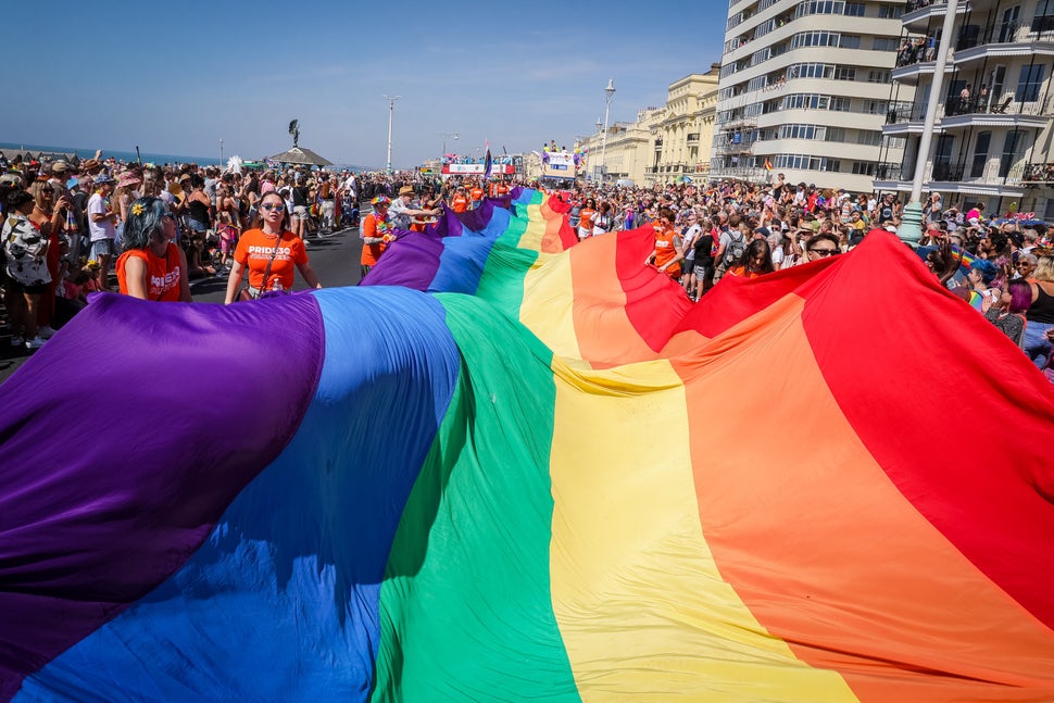 BRIGHTON, ENGLAND - AUGUST 06: Festival goers watch a rainbow flag being carried at the Pride LGBTQ+ Community Parade – ‘Love, Protest & Unity’ during Brighton Pride on August 06, 2022 in Brighton, England. (Photo by Tristan Fewings/Getty Images)