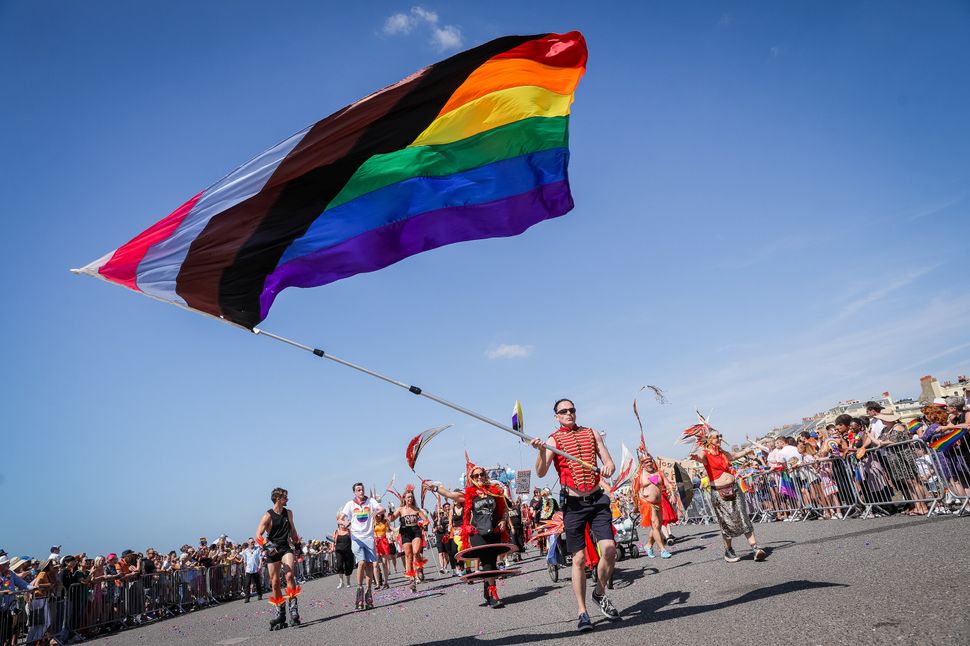BRIGHTON, ENGLAND - AUGUST 06: Festival goers watch a rainbow flag being carried at the Pride LGBTQ+ Community Parade – ‘Love, Protest & Unity’ during Brighton Pride on August 06, 2022 in Brighton, England. (Photo by Tristan Fewings/Getty Images)