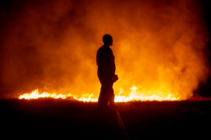Un vecino ante las llamas mientras colabora en las labores de extinción del incendio de Cures, en Boiro, A Coruña, en la madrugada de este sábado.