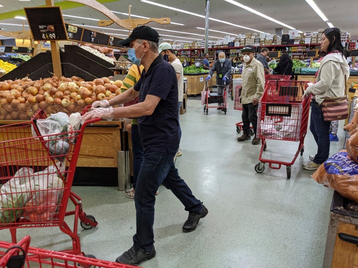 Several customers at Super King Markets grocery store wear face masks and gloves Friday, April 3, 2020, in Los Angeles, as protection against the coronavirus.(AP Photo/Damian Dovarganes)