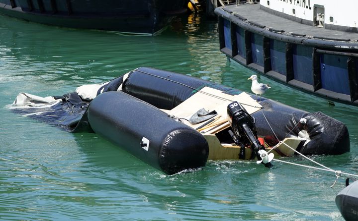 A partially submerged inflatable boat is brought into the marina after a group of people thought to be migrants are brought in to Dover by Border Force.