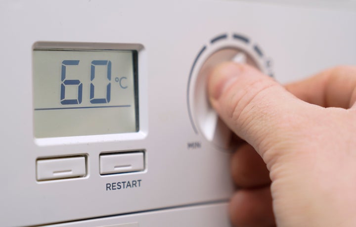 A homeowner turning down the temperature of a gas boiler.