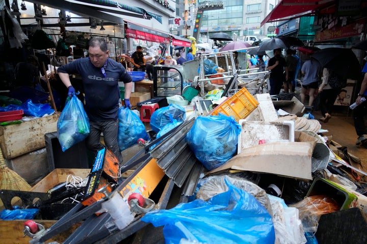 A shop owner carries debris after the water drained from a submerged traditional market following heavy rainfall in Seoul, South Korea, on Aug. 9, 2022.