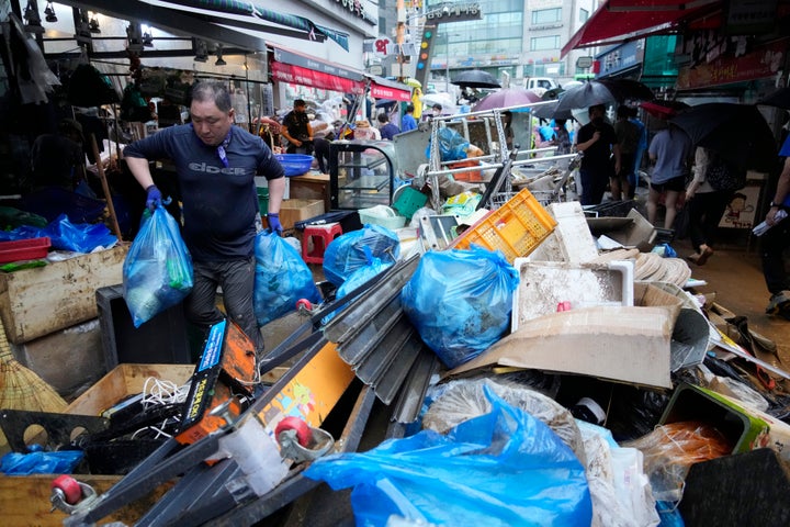 A shop owner carries debris after the water drained from a submerged traditional market following heavy rainfall in Seoul, South Korea, on Aug. 9, 2022. 