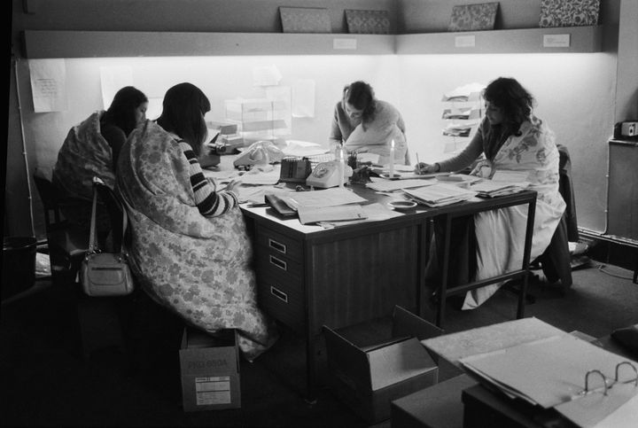 Four women working in an office in London during the power cuts of 1973 and 1974. They work for Slumberdown and are able to wrap themselves in Slumberdown quilts to keep warm.