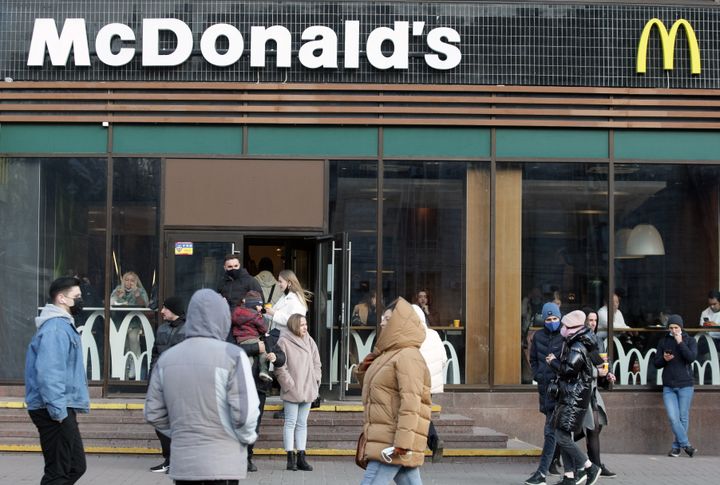 Ανθρωποι περνούν δίπλα από το λογότυπο McDonald's σε ένα εστιατόριο στο Κίεβο.