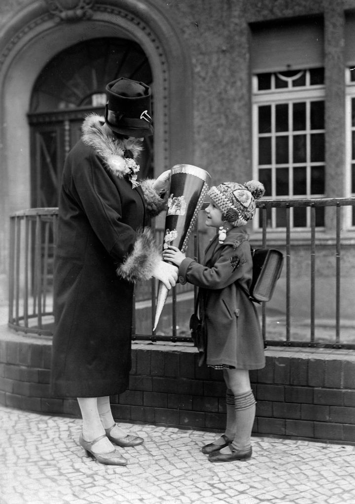 A mother passes a school cone to her daughter in 1927.