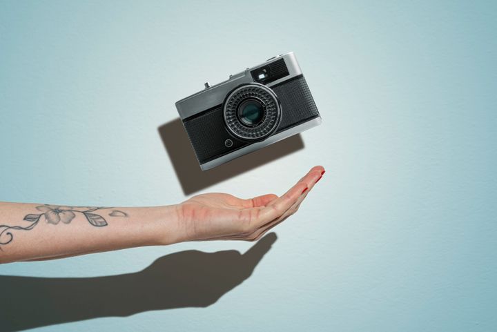 Woman hand throwing a vintage camera.Studio shot