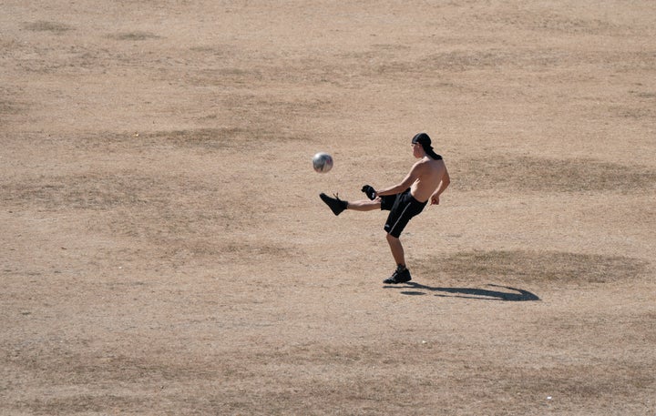 People play football on parched grass on Parker's Piece in Cambridge.