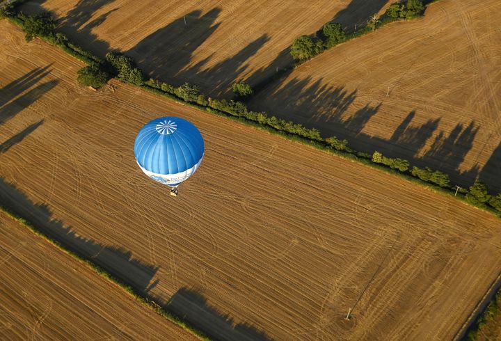 A balloon flies above dry fields at the annual Bristol International Balloon Fiesta.
