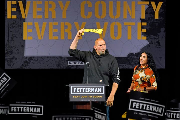 Fetterman greets the crowd as his wife, Gisele Barreto Fetterman, looks on. Gisele delivered introductory remarks that were a hit with the crowd.