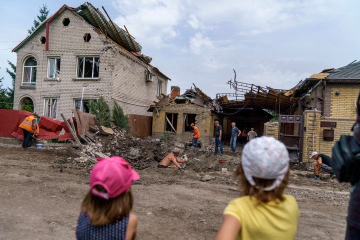 Children watch as workers clean up after a rocket strike on a house in Kramatorsk, Donetsk region, on Aug. 12. There were no injuries reported in the strike.