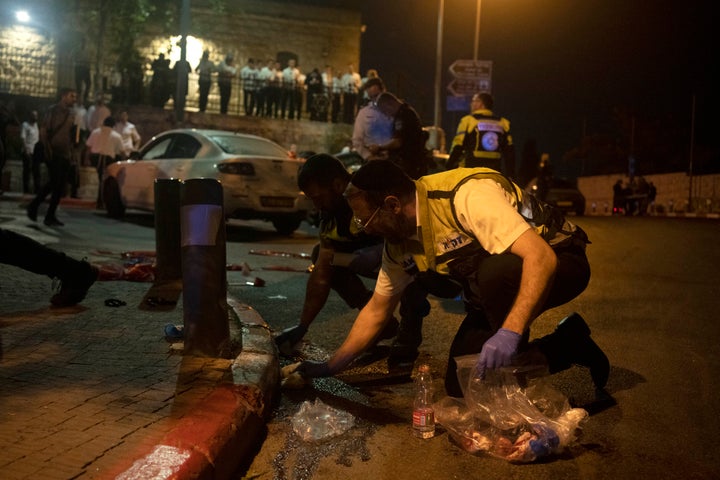 Volunteers with Zaka rescue service clean blood from the scene of a shooting attack that wounded several Israelis near the Old City of Jerusalem, early Sunday, Aug. 14, 2022. (AP Photo/ Maya Alleruzzo)