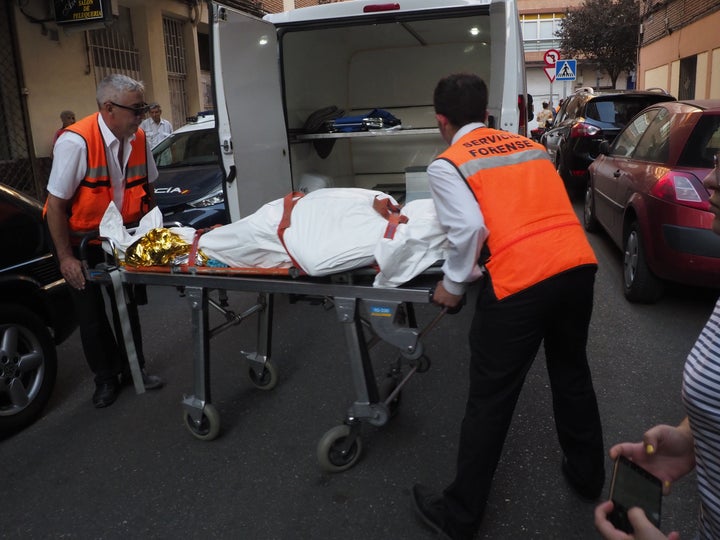 Miembros del servicio forense retirando el cuerpo de una de las víctimas.