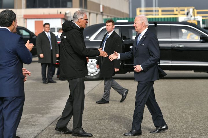 President Joe Biden (R) shakes hands with Governor of Washington Jay Inslee (D) upon arrival at Seattle-Tacoma International Airport in Seattle, Washington, on April 21.