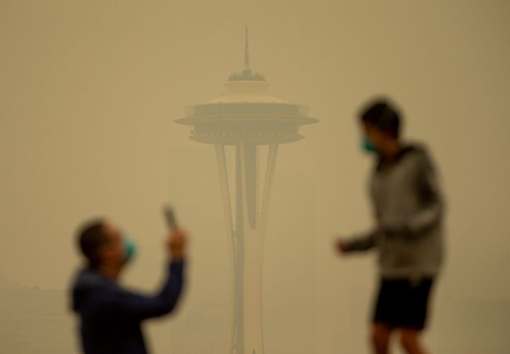 People take photos against the backdrop of the Space Needle as smoke from wildfires fills the air at Kerry Park on Sept. 12, 2020, in Seattle, Washington.