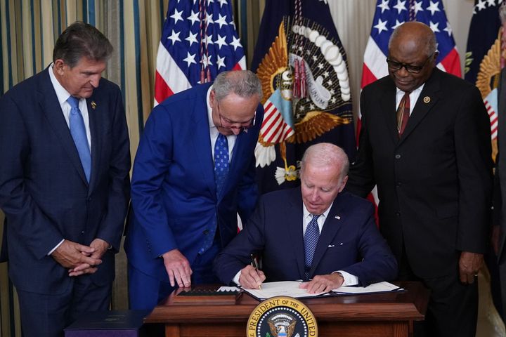 Sen. Joe Manchin (D-W.Va.), Senate Majority Leader Chuck Schumer (D-N.Y.) and House Majority Whip James Clyburn (D-S.C.) watch President Joe Biden sign the Inflation Reduction Act of 2022 into law during a ceremony in the State Dining Room of the White House on Aug. 16.