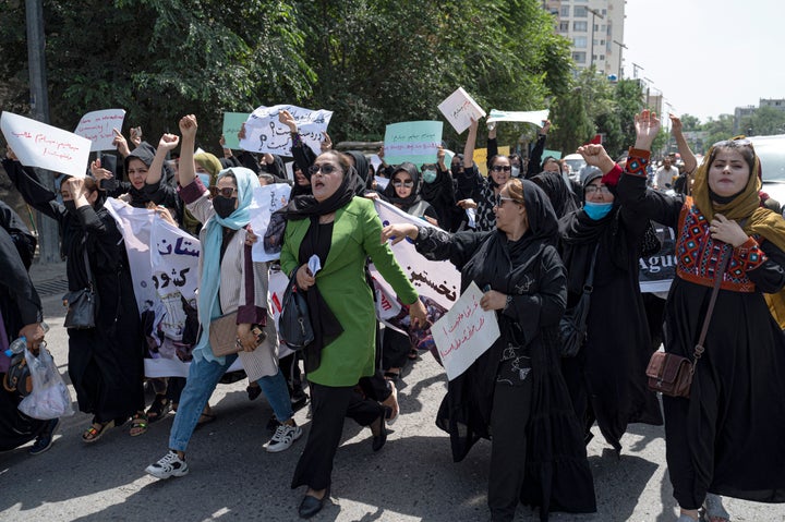 Afghan women hold placards as they march and shout slogans "Bread, work, freedom" during a womens' rights protest in Kabul on August 13, 2022. - Taliban fighters beat women protesters and fired into the air on Saturday as they violently dispersed a rare rally in the Afghan capital, days ahead of the first anniversary of the hardline Islamists' return to power.