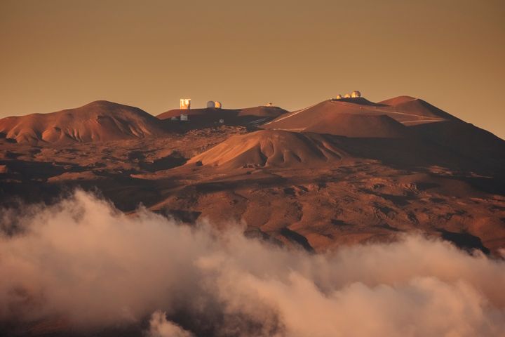 Dramatic evening light shines above the clouds on the observatory and its large astronomical telescopes on the dormant volcano of Mauna Kea in Hawaii. Mauna Kea is considered sacred by native Hawaiians, who want more control over how the mountain is used by scientists.
