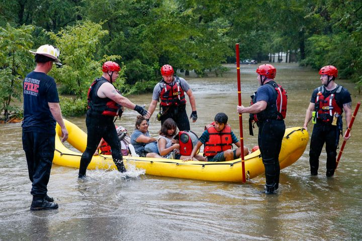 Members of the Balch Springs Fire Department bring a family of four, who did not wish to be named, by boat to higher ground after rescuing them from their home along Forest Glen Lane in Balch Springs, Texas, Monday, Aug. 22, 2022. Over 9 inches of rain were reported in the last 24 hours at DFW Airport. (Elías Valverde II/The Dallas Morning News via AP)