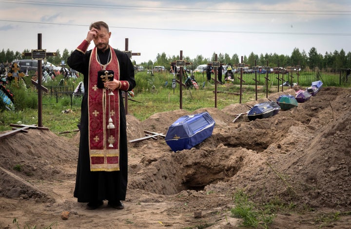Orthodox priest Father Andriy prays for unidentified civilians killed by Russian troops during Russian occupation in Bucha, on the outskirts of Kyiv, Ukraine, on Aug. 11, 2022.