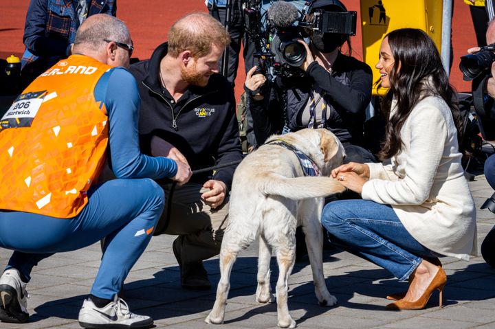 The Duke and Duchess of Sussex meet a dog as they attend the Invictus Games on April 17 in the Netherlands.