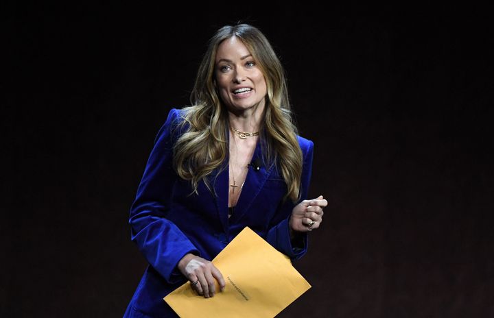 Olivia Wilde holds an envelope reading "personal and confidential" as she speaks onstage during CinemaCon 2022.