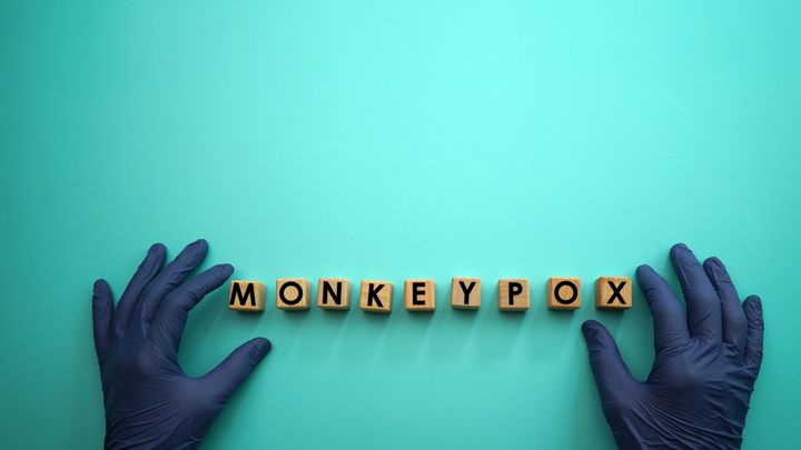 monkeypox word block with medical gloves and blue background