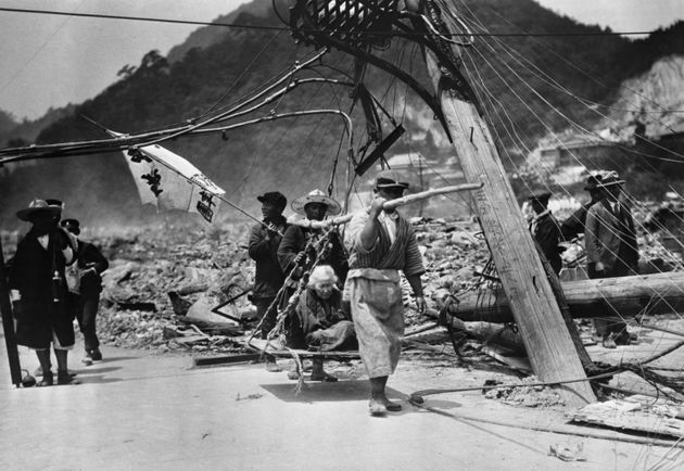 日本赤十字社が即席の担架で女性を廃墟から運ぶ様子