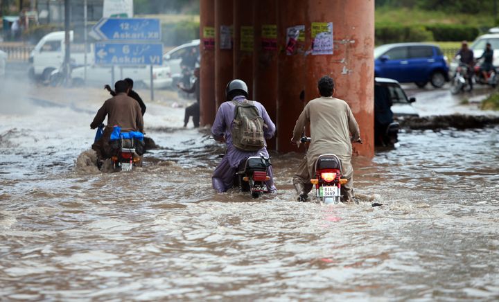 大雨で、バイクの運転は困難に（2022年6月18日、パキスタン・ラワルピンディで撮影）