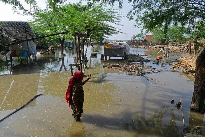 Flood-affected people wade outside their flooded houses at Shikarpur in Sindh province on Tuesday