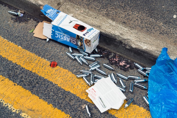 Discarded small nitrous oxide canisters and dispenser packaging from the use of the 'legal high' also known as NOS.