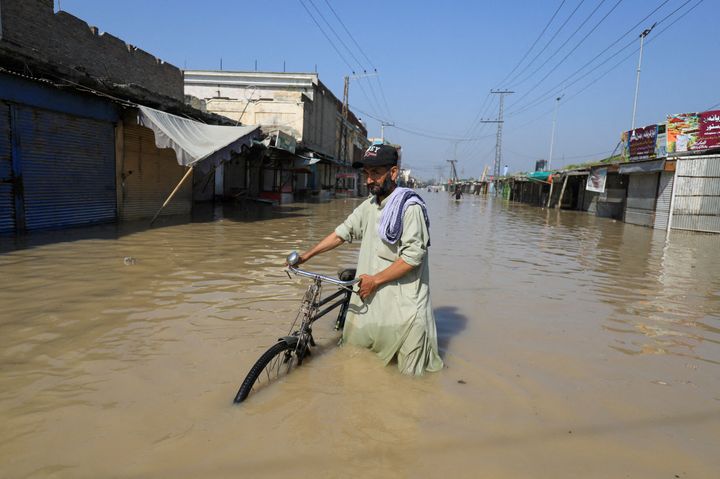 Ένας άνδρας περπατά με το ποδήλατο του στα νερά της πλημμύρας μετά από βροχές κατά την περίοδο των μουσώνων στη Nowshera, Πακιστάν, 29 Αυγούστου 2022.