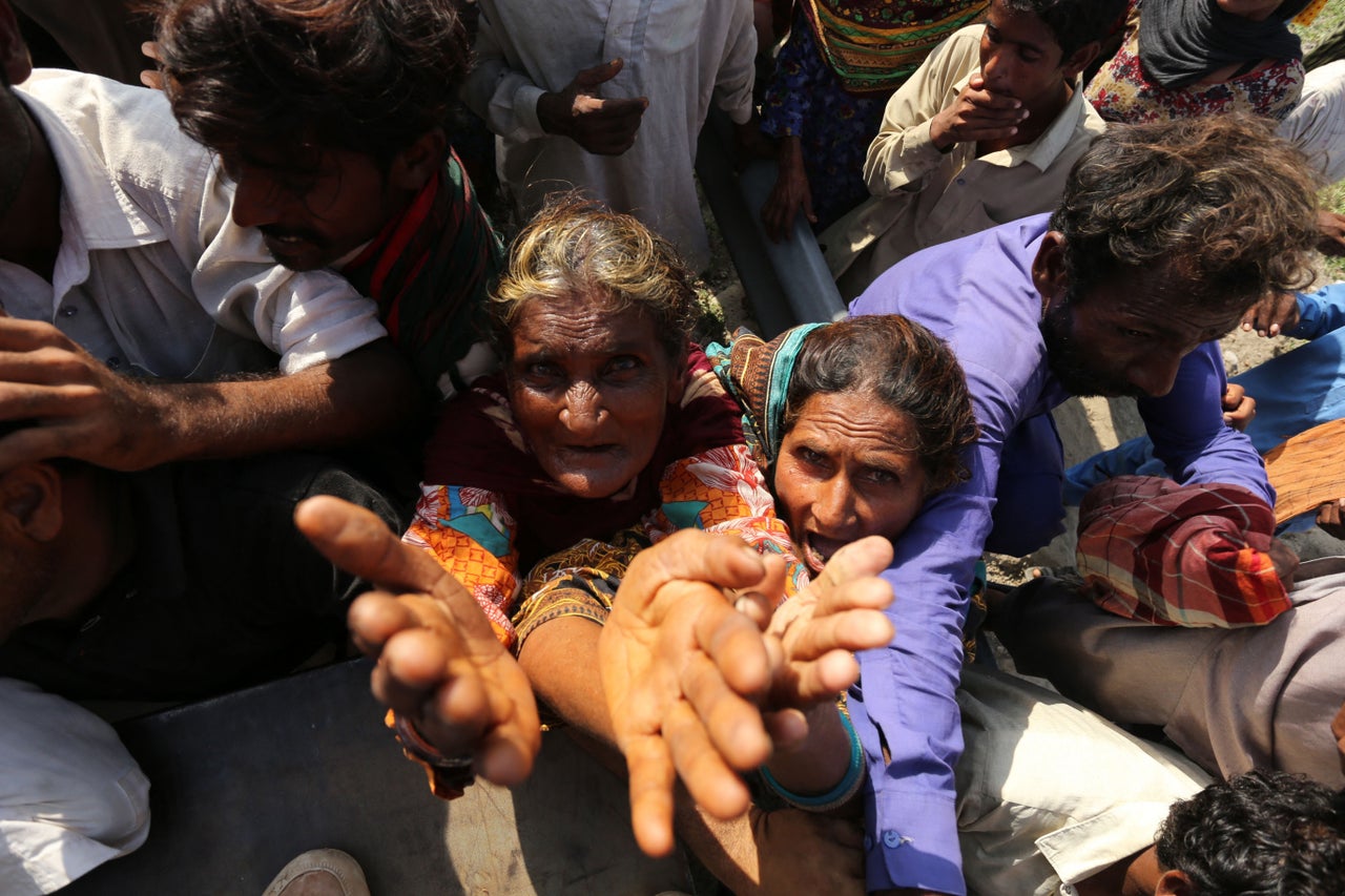 Displaced people wait to receive relief food box in a flood hit area following heavy monsoon rains in Dera Ghazi Khan district of Punjab province on Aug. 29, 2022.