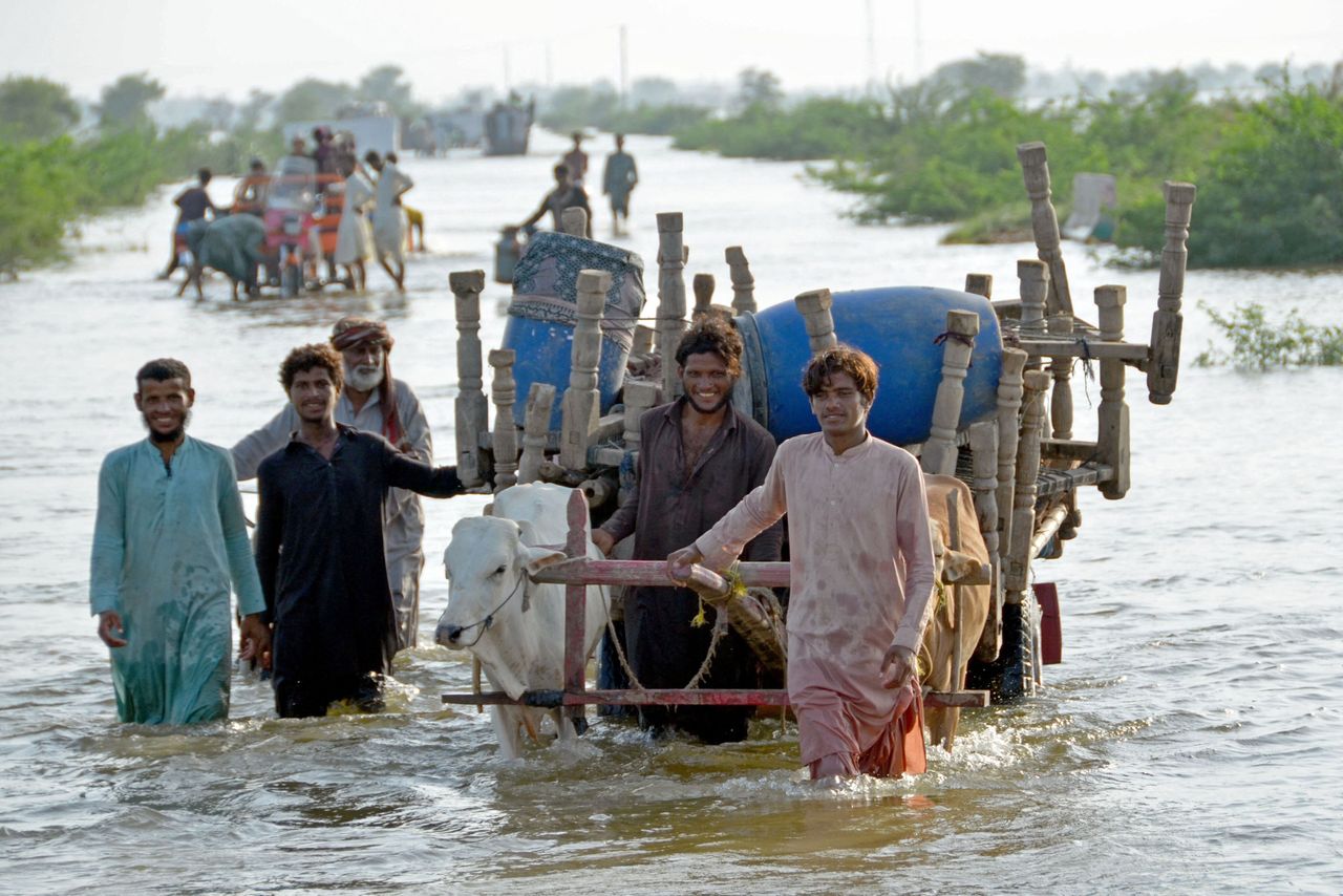 Stranded people along with their belongings wade through a flooded street after fleeing from their flood hit homes following heavy monsoon rains at Sohbatpur area in Jaffarabad district of Balochistan province on Aug. 28, 2022. Pakistan's flooded southern Sindh province braced on August 28 for a fresh deluge from swollen rivers in the north as the death toll from this year's monsoon topped 1,000.