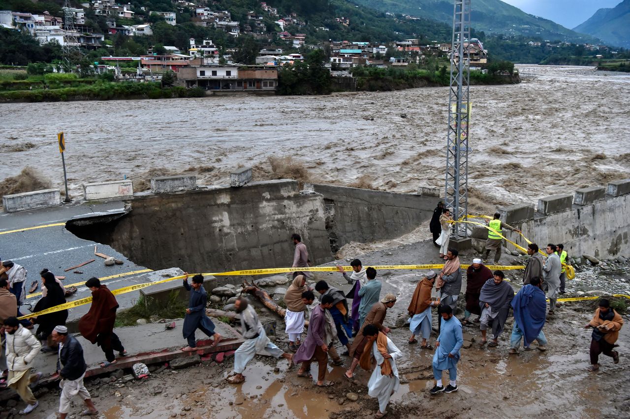 People gather in front of a road damaged by flood waters following heavy monsoon rains in Madian area in Pakistan's northern Swat Valley on Aug. 27, 2022.