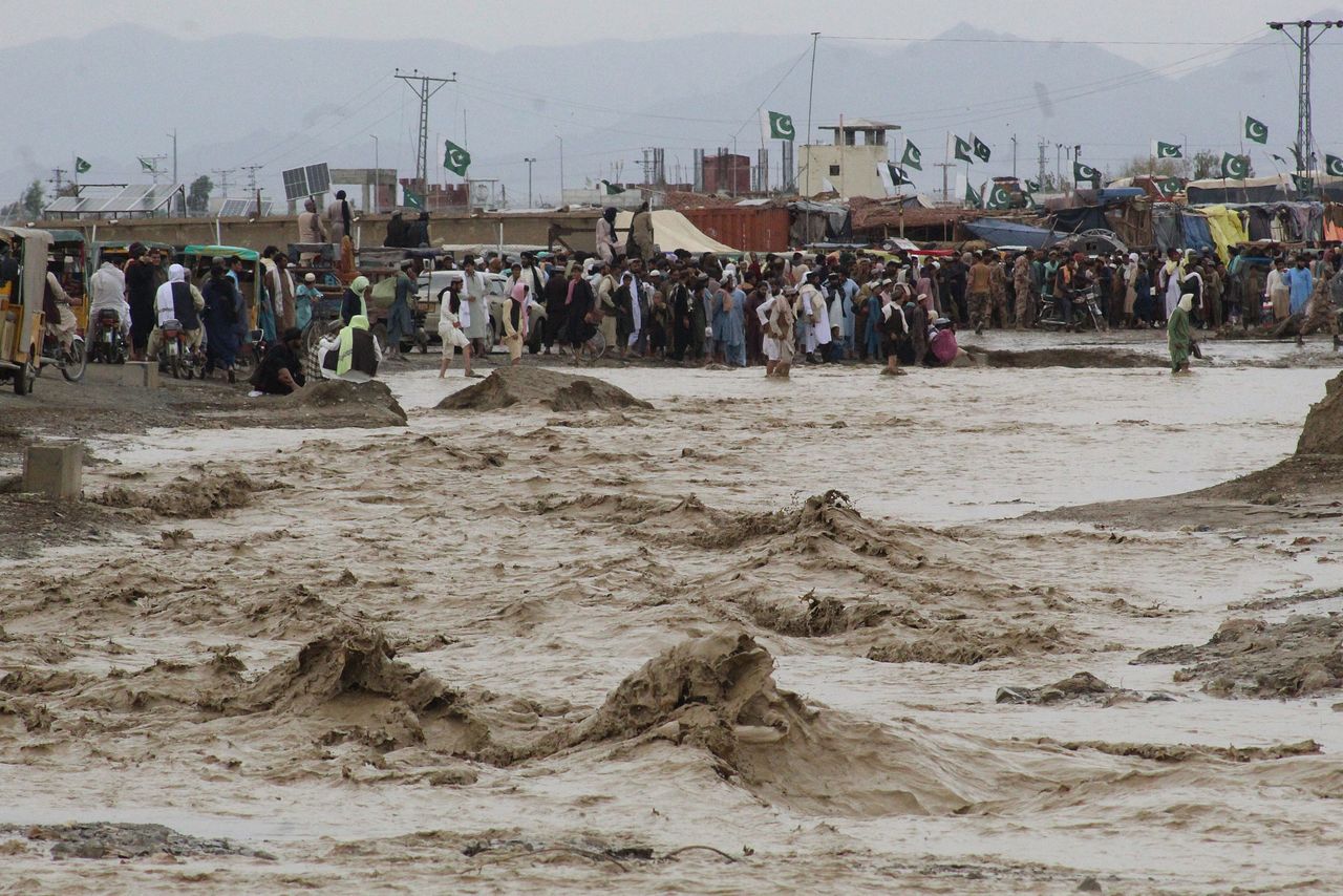 People wade through flooded mud water after heavy monsoon rainfall in the border town of Chaman in Balochistan province on Aug. 25, 2022.
