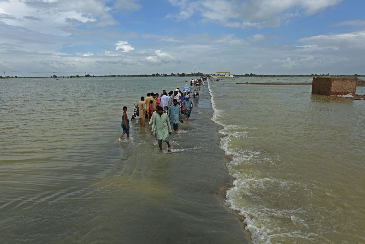 Stranded people wade through a flooded area after heavy monsoon rainfall in Rajanpur district of Punjab province on Aug. 25, 2022.
