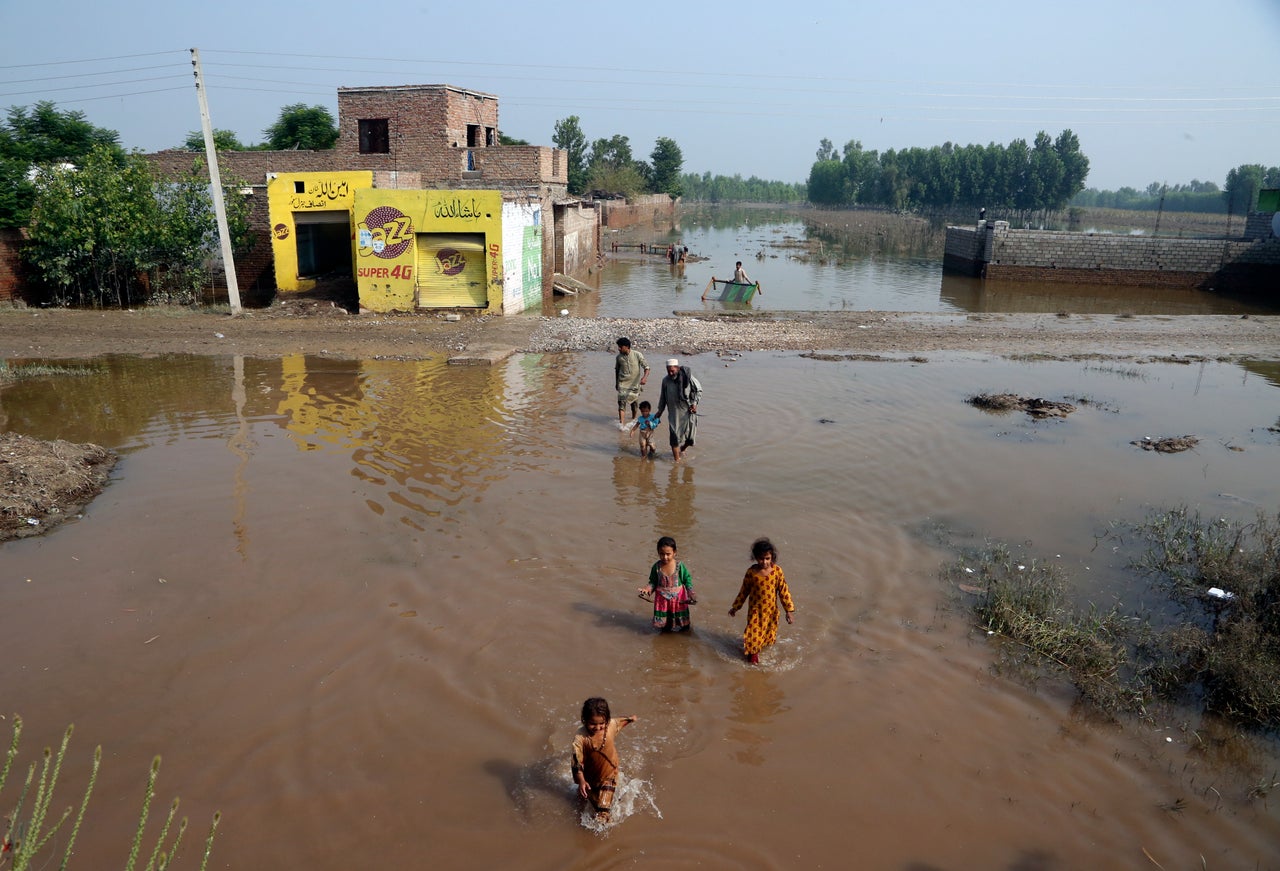People wade through floodwaters, in Charsadda, Pakistan on Aug. 31, 2022.
