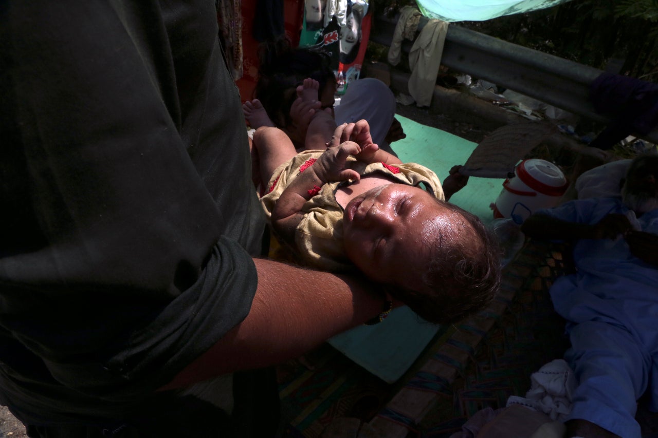 A mother carries her sick baby after floodwaters hit her home, in Charsadda, Pakistan on Aug. 31, 2022.