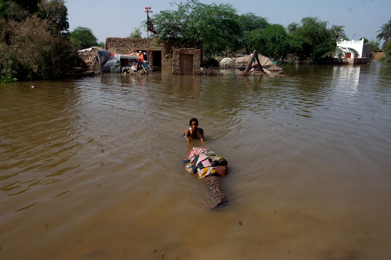 A man carries salvageable belongings from his flood-hit home in Shikarpur district of Sindh province on Aug. 31, 2022. 