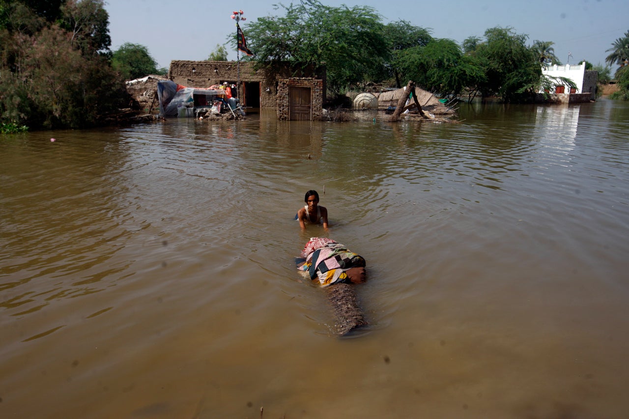 A man carries salvageable belongings from his flood-hit home in Shikarpur district of Sindh province on Aug. 31, 2022.