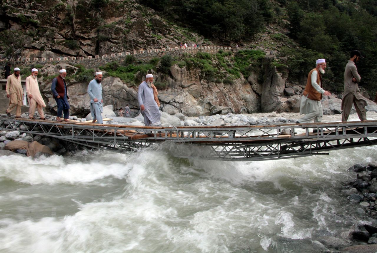 People cross a river on a bridge damaged by floodwaters, in the town of Bahrain, Pakistan on Aug. 30, 2022. The United Nations and Pakistan issued an appeal Tuesday for $160 million in emergency funding to help millions affected by record-breaking floods that have killed more than 1,150 people since mid-June.