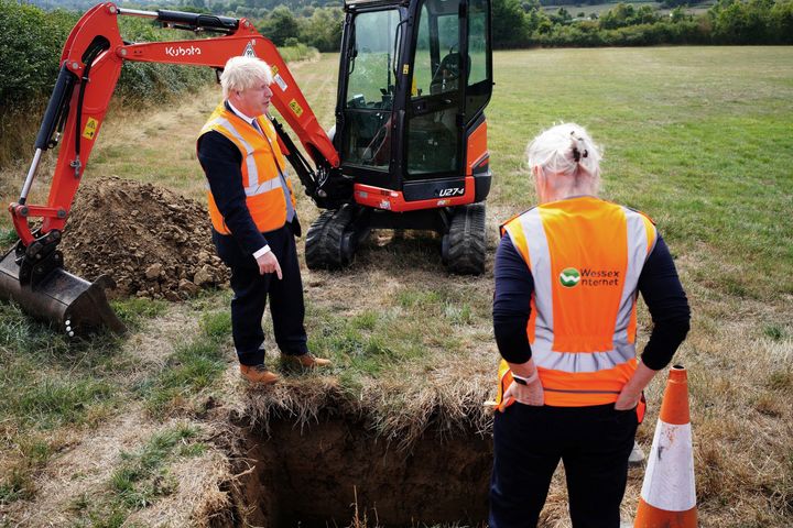 Britain's Prime Minister Boris Johnson (L) and Britain's Culture Secretary Nadine Dorries (R) look at a hole during a visit to the Henbury Farm in north Dorset, on August 30, 2022 as Wessex Internet company is laying fibre optics in the field. - Boris Johnson's visit marks a new data showing that 70 percent of the United Kingdom is now benefiting from gigabit broadband coverage. (Photo by Ben Birchall / POOL / AFP) (Photo by BEN BIRCHALL/POOL/AFP via Getty Images)