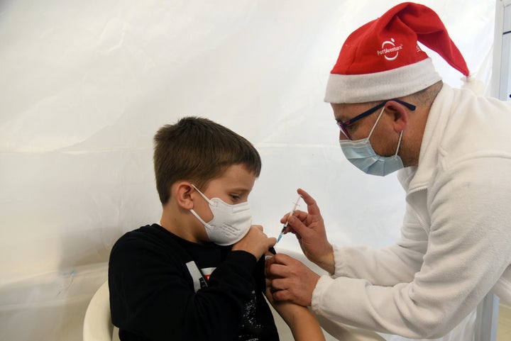 Un sanitario con gorro de Papá Noel vacuna a un niño el 18 de diciembre de 2021 en Tarragona.