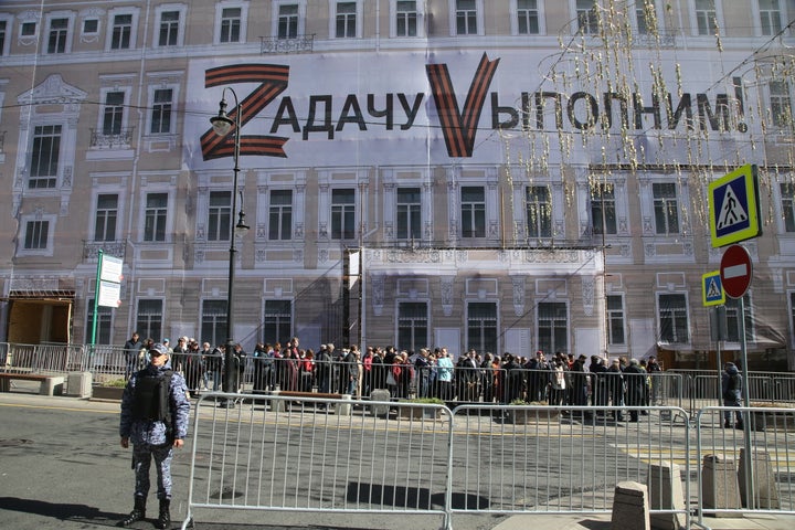 People line up to pay their last respects to the late USSR President Mikhail Gorbachev as a pro-war propaganda sign reading "we will complete the task" and symbols of the military invasion of Ukraine — the letters "Z" and "V" — are seen plastered across the side of the building.